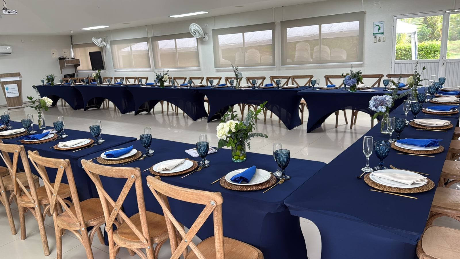 Salón montado con sillas cross back, mesas vestidas y cristalería para evento en Barranquilla